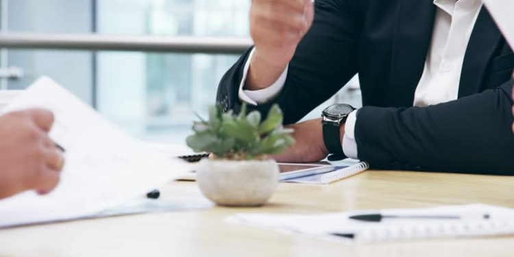 4k video footage of three unrecognizable business colleagues going over paperwork during a meeting in the boardroom